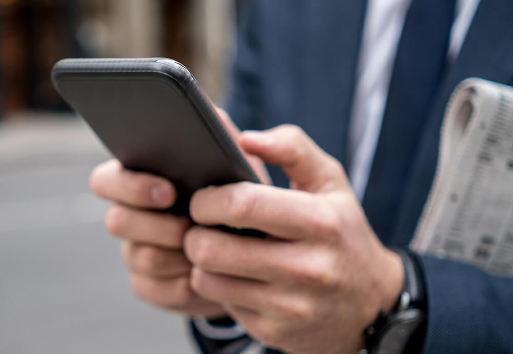 Geschäftsmann liest in seinem Handy aktuelle Neuigkeiten über IP Concept.