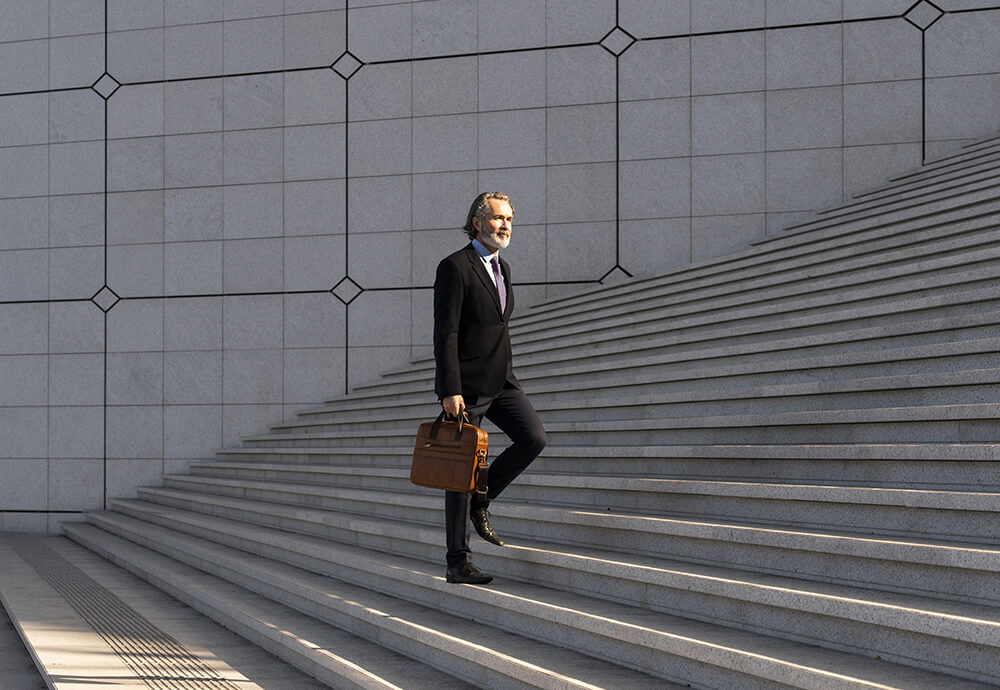 Geschäftsmann steigt eine Treppe hinauf – Transparenz und Struktur im Fondsreporting mit IP Reporting.