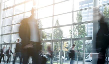 Menschen in Bewegung in heller Glaslobby – Karriere, Entwicklung und Chancen bei IPConcept.