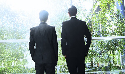 Zwei Geschäftsleute im Anzug blicken ins Grüne – Verantwortung und Nachhaltigkeit bei IPConcept.