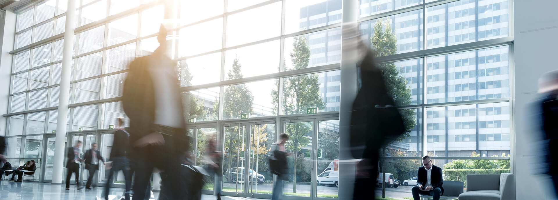 Menschen in Bewegung in heller Glaslobby – Karriere, Entwicklung und Chancen bei IPConcept.