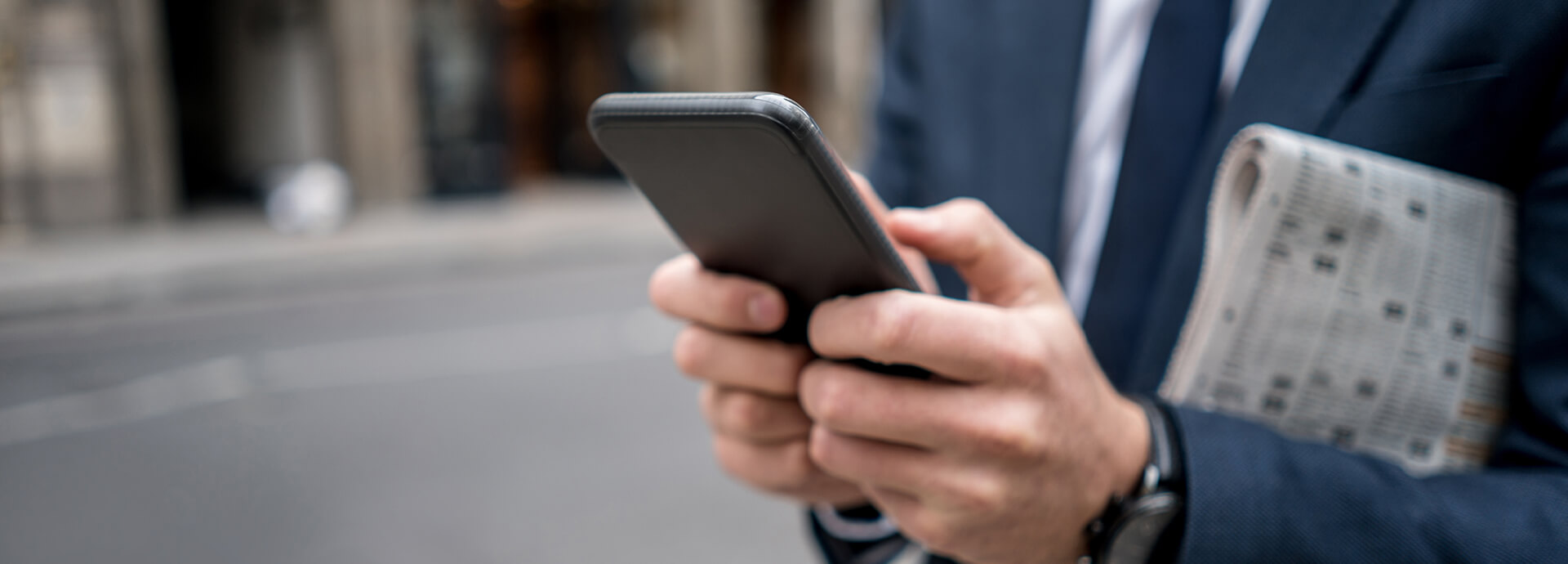 Geschäftsmann liest in seinem Handy aktuelle Neuigkeiten über IP Concept.